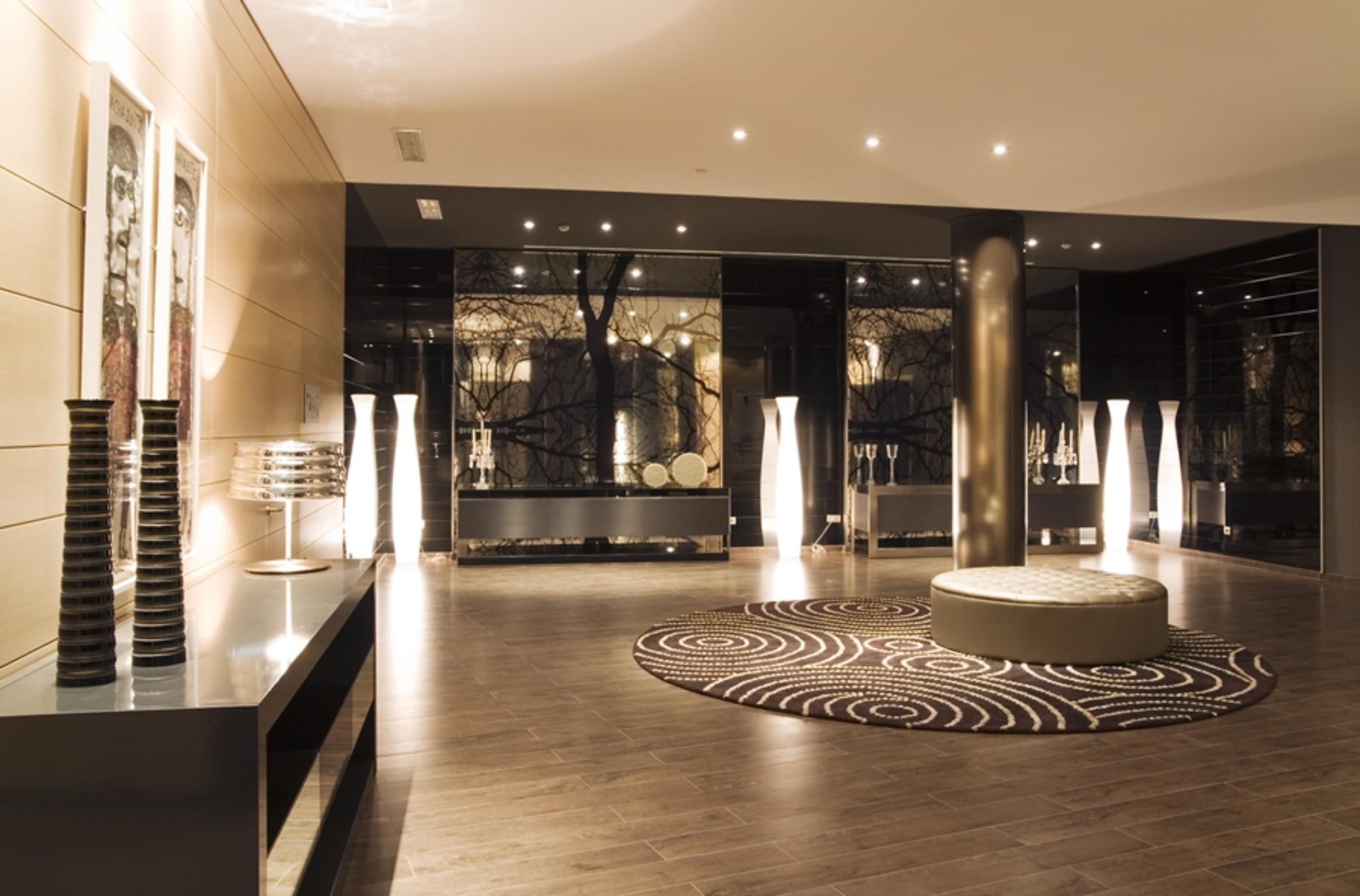 Eurostars Palace Κόρδοβα Εξωτερικό φωτογραφία The photo shows a modern interior space, likely a lobby or waiting area. The design features polished wooden flooring and sleek surfaces. There are tall, artistic light fixtures scattered throughout, contributing to a sophisticated ambiance. A round 