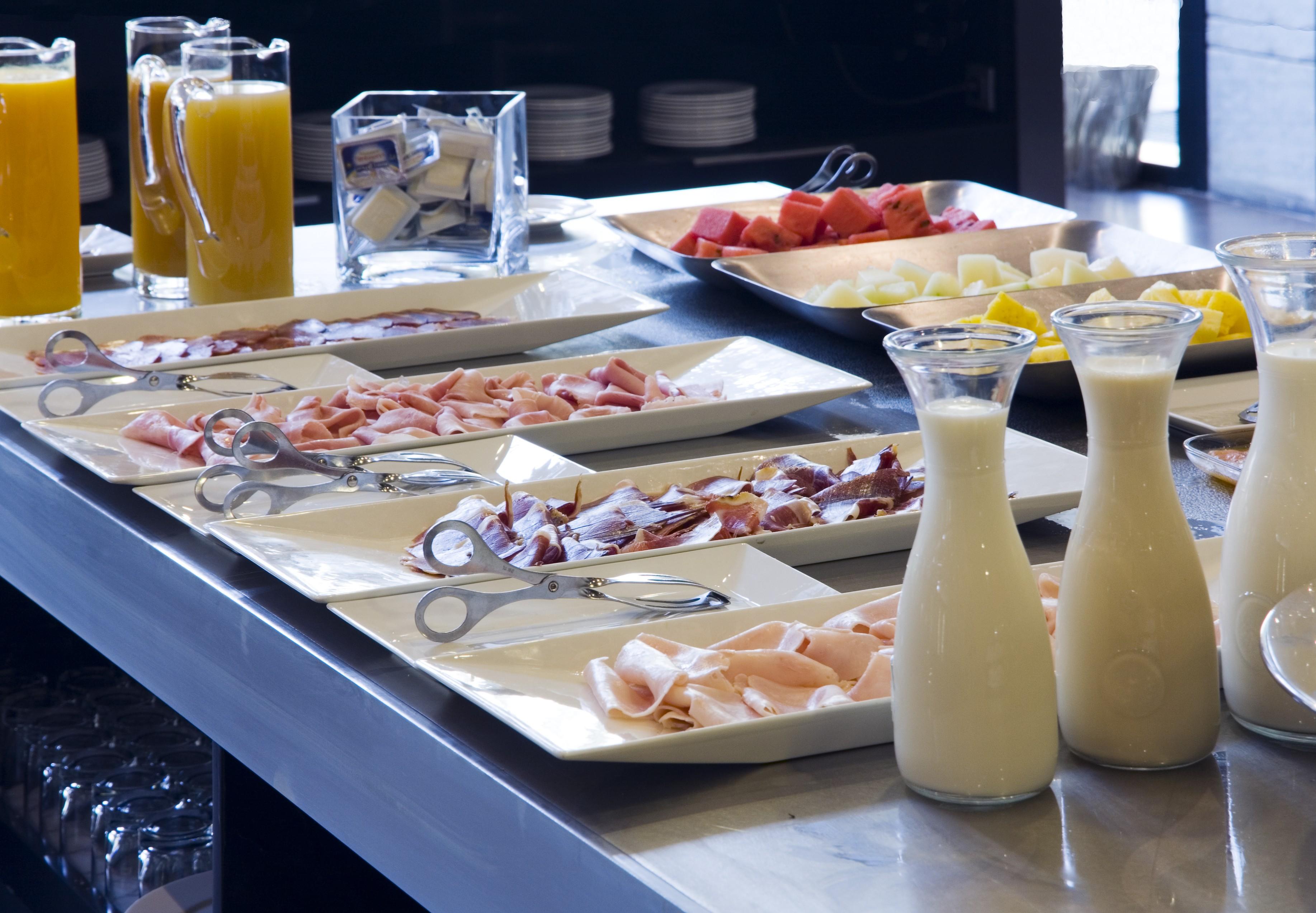 Eurostars Palace Κόρδοβα Εξωτερικό φωτογραφία The photo displays a buffet area with various food items arranged on a countertop. There are multiple plates featuring an assortment of sliced meats, likely including ham and possibly turkey or chicken. Additionally, two glass pitchers are filled wit