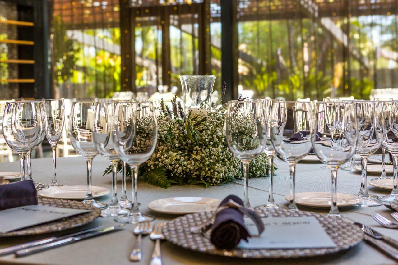 Eurostars Palace Κόρδοβα Εξωτερικό φωτογραφία The photo displays an elegantly set dining table arranged for a formal event. The table is adorned with a centerpiece made of white flowers and greenery, surrounded by numerous glassware, including wine glasses and water goblets. Each place setting i